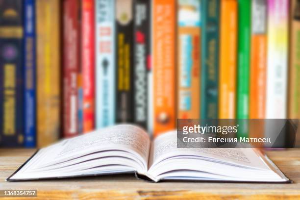 close-up of opened book on bookshelf on blurred books background. home library reading books concept - boek stockfoto's en -beelden