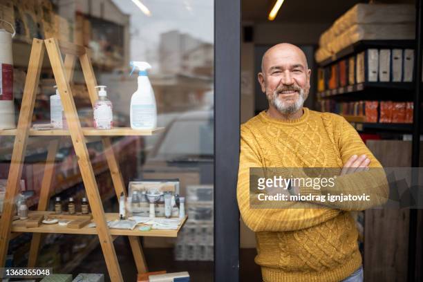 proud owner standing with arms crossed in front of his store - store bildbanksfoton och bilder