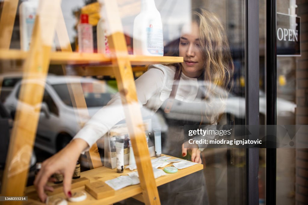 Saleswoman line up the new products on the shelf in the store