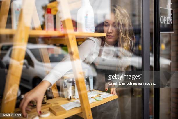 saleswoman line up the new products on the shelf in the store - store window stock pictures, royalty-free photos & images
