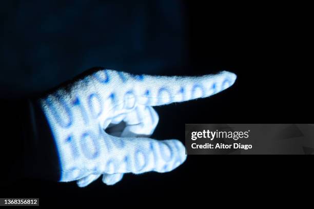 hand with white glove and a binary code based on zeros and ones on its surface with pointing out with the index finger to something or by virtually pressing a button . represents man and machine, programming, the virtual world and the future. - tapping points stockfoto's en -beelden