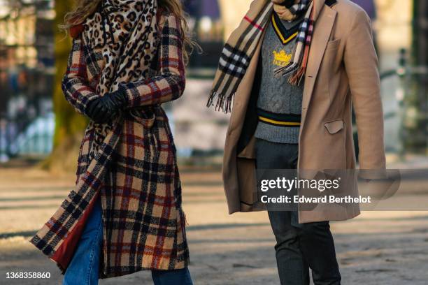 Passerby wears a beige / camel / black leopard print pattern scarf, a beige / burgundy / black checkered print pattern belted long coat, black shiny...