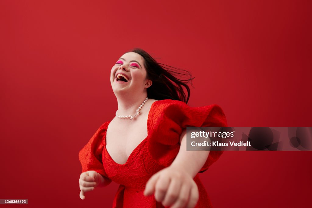 Young woman laughing against red background