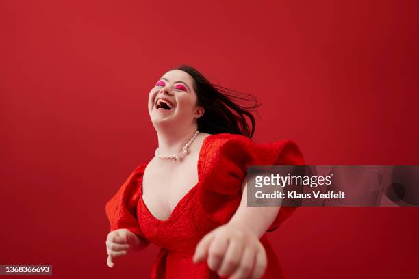 young woman laughing against red background - down's syndrome stockfoto's en -beelden