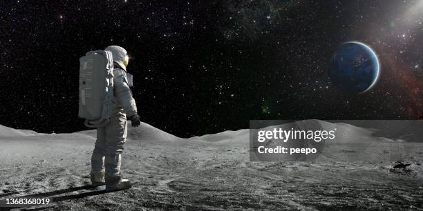 astronaut, der auf dem mond steht und auf eine ferne erde schaut - astronaut helmet stock-fotos und bilder