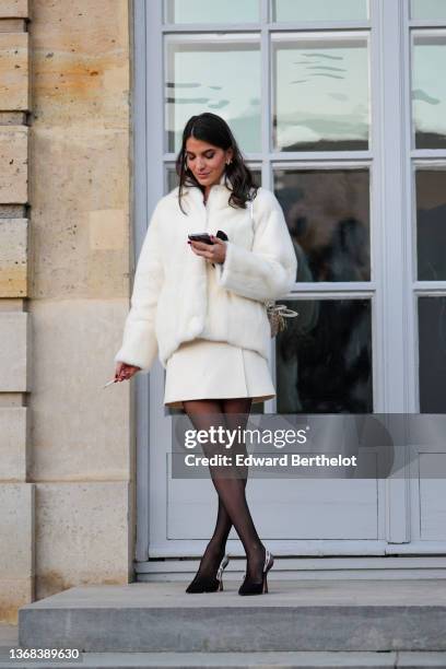 Guest wears gold bee earring, a white fluffy / fur coat, a white short skirt, black fishnet tights, black suede pointed J'Adior slingback pumps heels...