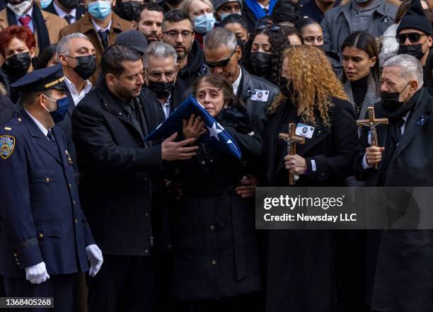 Amalia Mora, mother of slain NYPD officer Wilbert Mora, is surrounded by family members and weeps holding the American flag she received from the...