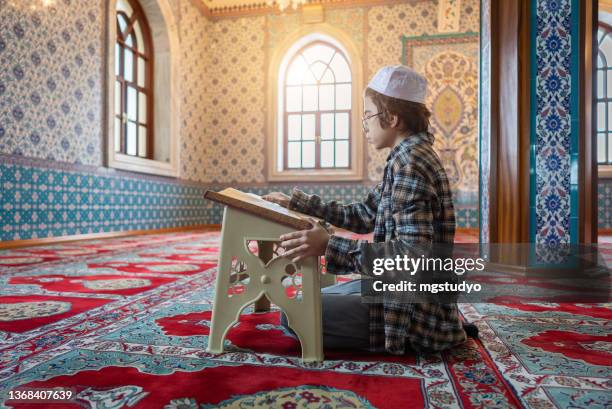 turkish muslim young boy reading the holy book koran in mosque - quran stock pictures, royalty-free photos & images