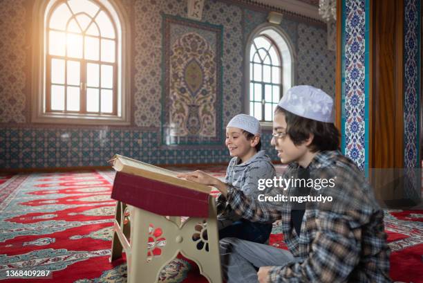 happy muslim young kid read quran together in mosque. - koran stock pictures, royalty-free photos & images