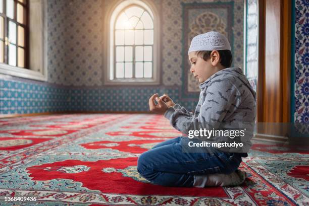 süßer kleiner muslimischer junge, der in der moschee betet - namaz stock-fotos und bilder