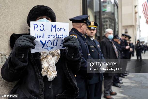 Outside the funeral of slain NYPD officer Wilbert Mora, a women holds a sign reading, "P.O. Mora died protecting you!" at St. Patrick's Cathedral in...