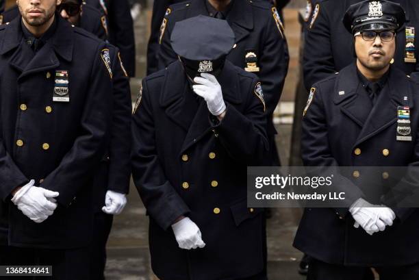 An NYPD officer bows their head as the casket of fallen NYPD officer Wilbert Mora is brought out of St. Patrick's Cathedral in Manhattan on February...
