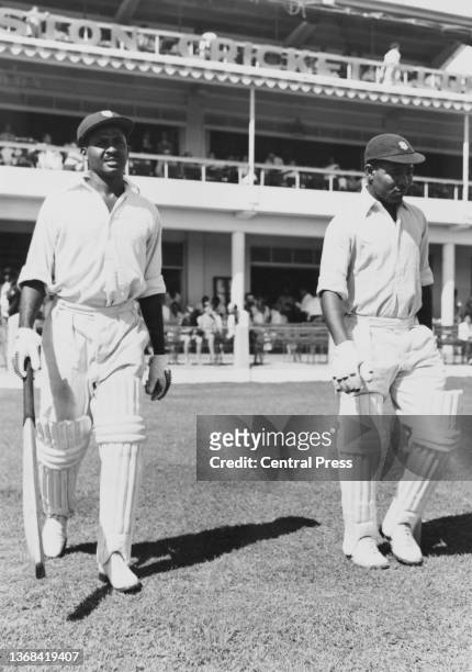John Holt from Jamaica and Everton Weekes from Barbados, right handed batsmen for the West Indies cricket team walk out from the pavilion to continue...