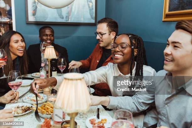 multiracial female and male friends having food at table in restaurant - leaving work stock pictures, royalty-free photos & images