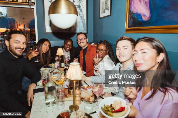 portrait of smiling multiracial male and female friends during dinner party at bar - reunião de amigos imagens e fotografias de stock