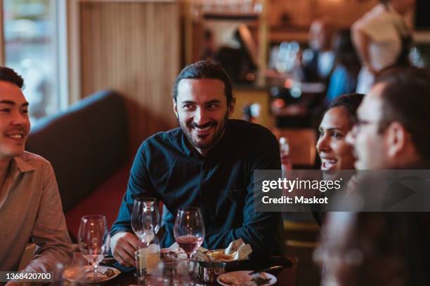 happy multiracial male and female friends having wine in restaurant - afterwork photos et images de collection