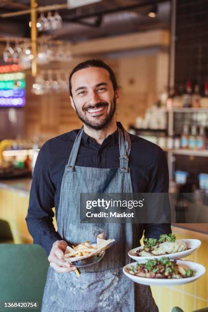 portrait of smiling male waiter with food in restaurant - servitör bildbanksfoton och bilder