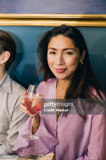 portrait of smiling woman with wine sitting by male friend in bar - after work drinks stock-fotos und bilder