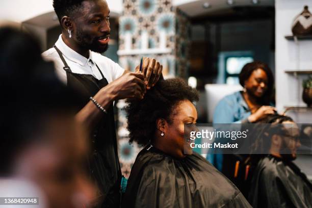 male hairdresser cutting hair of smiling female customer at barber shop - hairdressers black woman stock pictures, royalty-free photos & images