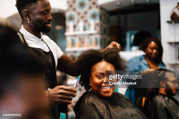 male barber cutting hair of happy female customer in salon - hairdressers black woman stock pictures, royalty-free photos & images