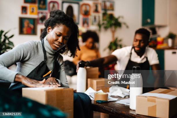 young female hairdresser labeling box in barber shop - small business stock pictures, royalty-free photos & images