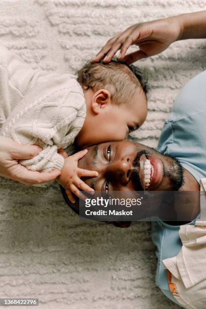 male toddler kissing father lying on blanket at home - vrouwen 32 jaar samen kus stockfoto's en -beelden