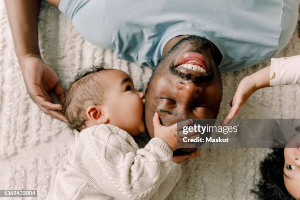 baby boy kissing father lying on blanket at home - genderblend fotografías e imágenes de stock