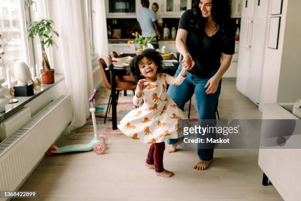 happy mother and daughter dancing in kitchen at home - black baby foto e immagini stock