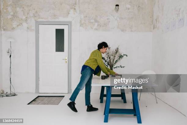 mature female entrepreneur arranging crockery on table in ceramics store - arrange stockfoto's en -beelden