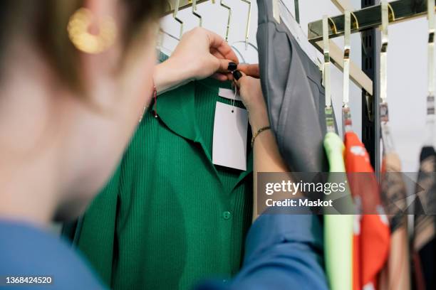 female owner tying price tag on clothes in store - middle east clothing stock pictures, royalty-free photos & images