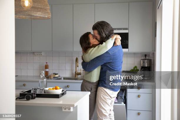 affectionate mature couple kissing on mouth at home - beso en la boca fotografías e imágenes de stock