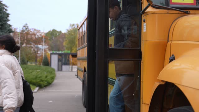 Joyful diverse pupils running out of school bus