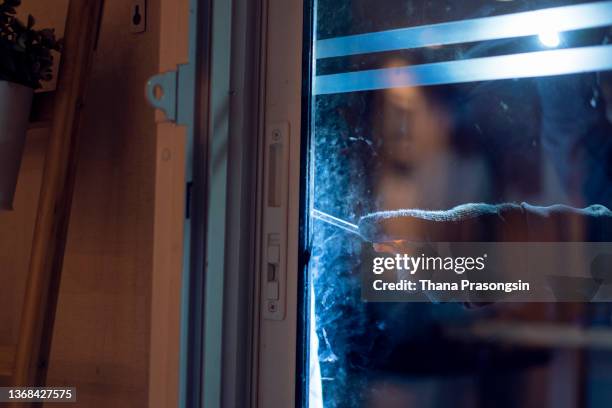 masked burglar holding flashlight while secretly entering into a house - einbruch stock-fotos und bilder