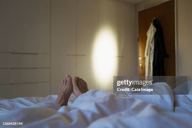 pov women with bare feet laying in bed - feet in bed stock-fotos und bilder