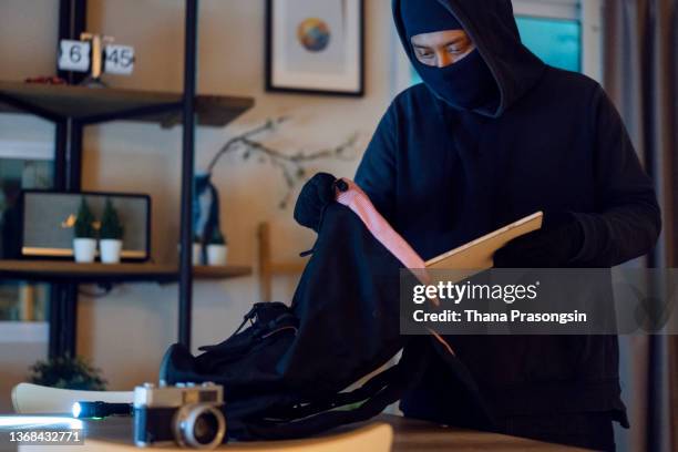 one man, criminal dressed all in black, carrying computer that he stole in house. - burglar carried stock pictures, royalty-free photos & images