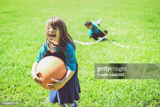 happy schoolchild on the playground with a huge ball, laughing and enjoying free time outdoors - kickball stock pictures, royalty-free photos & images