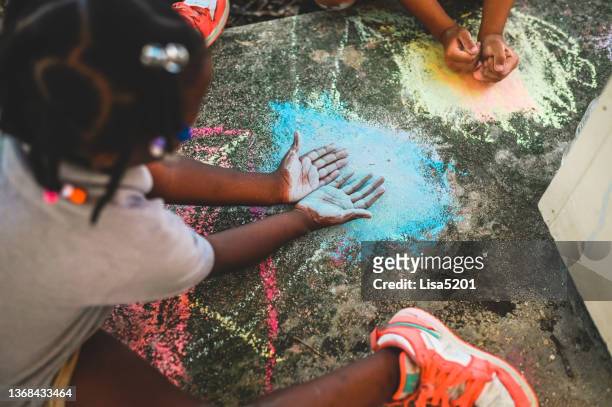 elementary age mixed race group of school child playing with sidewalk chalk outdoors - sidewalk chalk drawing stock pictures, royalty-free photos & images