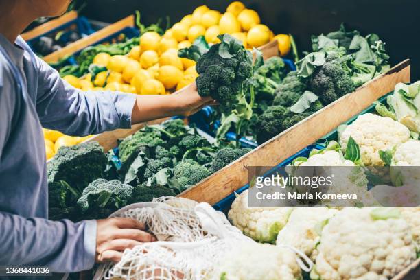 woman choosing greenery and vegetables at farmer market and using reusable eco bag. - crucifers stock pictures, royalty-free photos & images