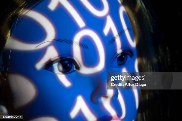 person with a white mask and a binary code on the mask. represents man and machine, programming, the virtual world and the future. - corporate media modern bright stockfoto's en -beelden