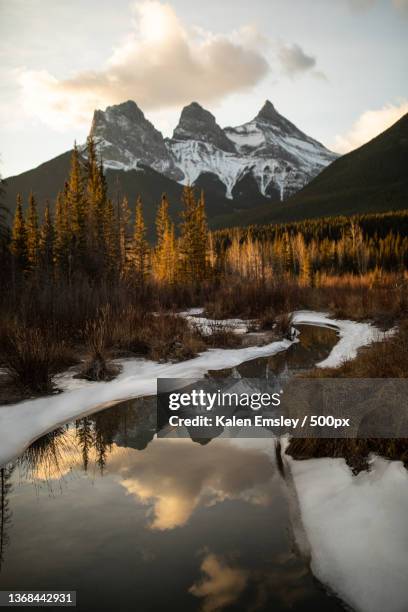 fall reflections,scenic view of lake by snowcapped mountains against sky,canmore,alberta,canada - canmore stockfoto's en -beelden