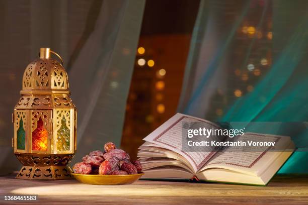 the muslim feast of the holy month of ramadan kareem. the holy quran placed with fanous and date fruits. blurred background with beautiful lights - lantern ramadan stock pictures, royalty-free photos & images