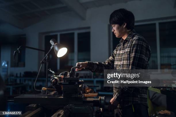 young japanese industrial man working indoors in metal workshop at night. - confident young man at work stock pictures, royalty-free photos & images