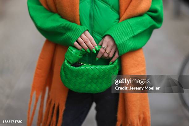 Sonia Lyson wearing Zara grey jeans, Zara green sweater and vest, Edited orange scarf, Bottega Veneta mini green Jodie bag on February 02, 2022 in...