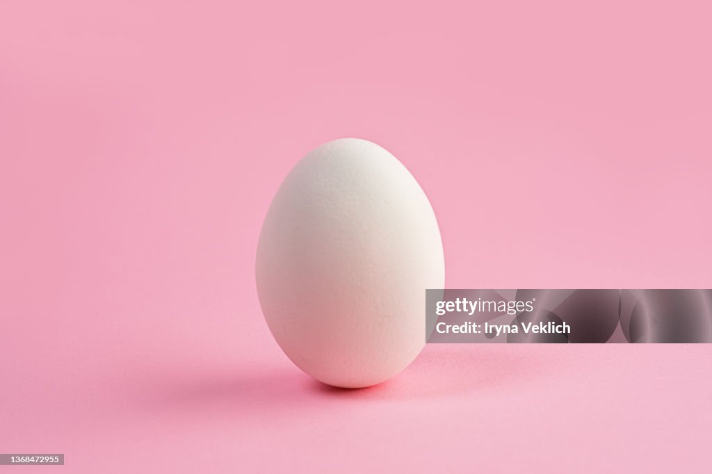 White color Easter Egg on pastel pink color background. Easter minimal concept.