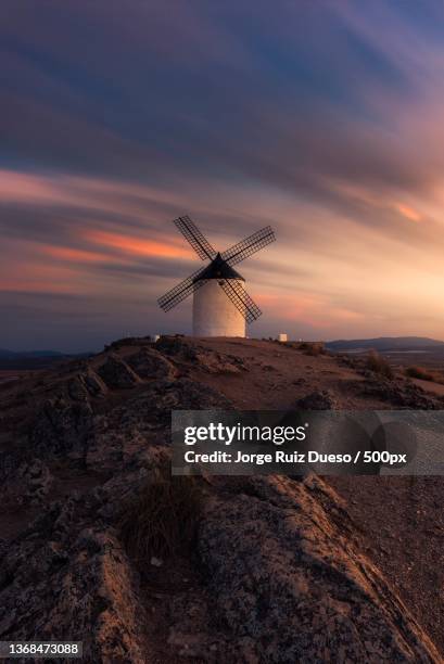 low angle view of windmill on field against sky during sunset,consuegra,spain - castilië la mancha stockfoto's en -beelden