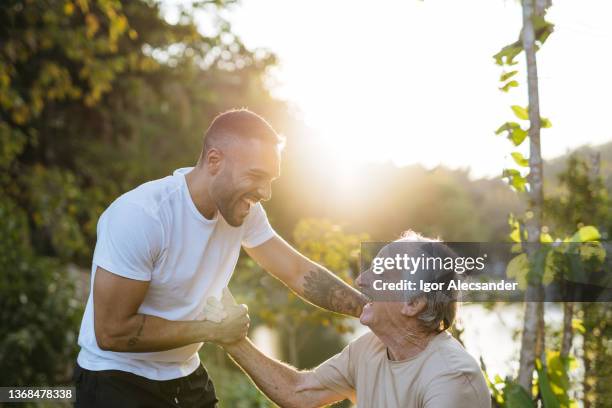 young and old athlete greet each other in the natural park - encouragement stock pictures, royalty-free photos & images