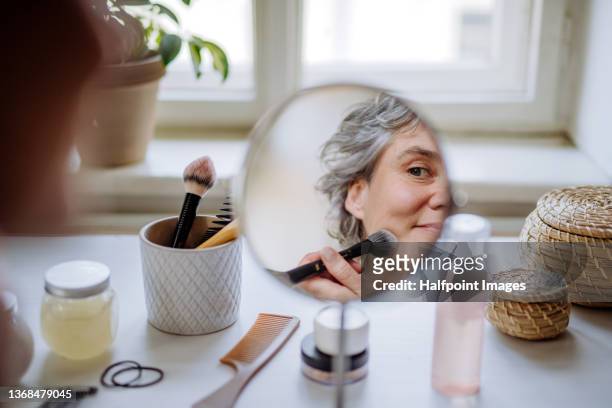 mature woman applying a make up at home. - makeup woman stockfoto's en -beelden