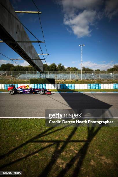 Australian Red Bull Racing Formula One team racing driver Daniel Ricciardo driving his RB9 racing car at speed underneath, and through the shadows of...