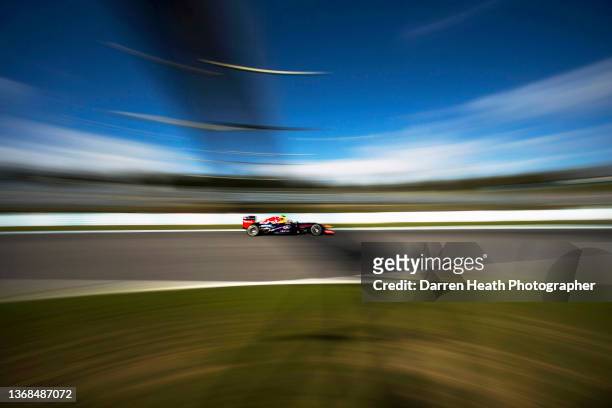 Australian Red Bull Racing Formula One team racing driver Daniel Ricciardo driving his RB9 racing car at speed underneath, and through the shadows of...