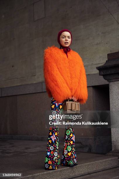 Emma Fridsell wearing colourful suit and bright orange fur coat and dark red knitted hat outside MKDT in Copenhagen fashion week Autumn/Winter 2022...